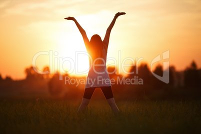 Girl with hands up on sunset background