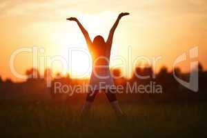 Girl with hands up on sunset background
