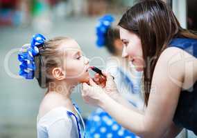 Mother putting lipstick on her daughter