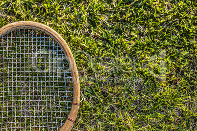 Vintage wood tennis racket on green grass garden
