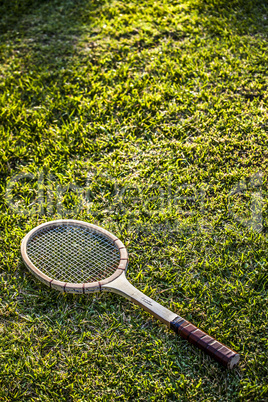 Vintage wood tennis racket on green grass garden