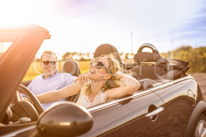 Mit dem Cabrio der Sonne entgegen - Verliebtes Paar lacht im Auto