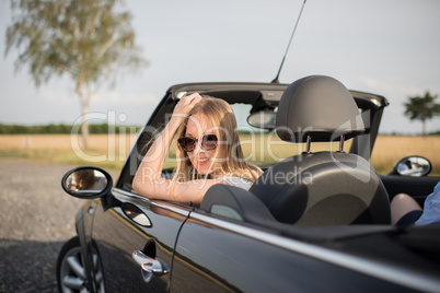 Spritztour im Cabrio - Junge Frau schaut aus einem Cabrio