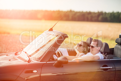 Mit dem Cabrio unterwegs - Verliebtes Paar im Cabrio lacht und ist glücklich