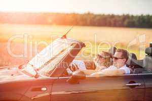 Mit dem Cabrio unterwegs - Verliebtes Paar im Cabrio lacht und ist glücklich