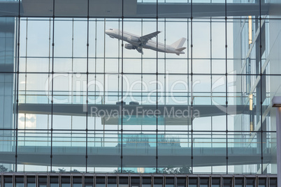 Bürogebäude Glasfassade im Hintergrund ein startendes Flugzeug