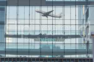 Bürogebäude Glasfassade im Hintergrund ein startendes Flugzeug