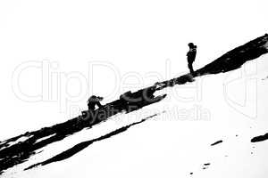 Man crawls towards man on rocky slope