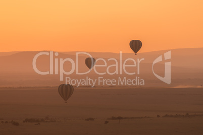 Three striped balloons fly over purple hills