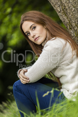 Beautiful Young Woman Sitting Leaning Against Tree