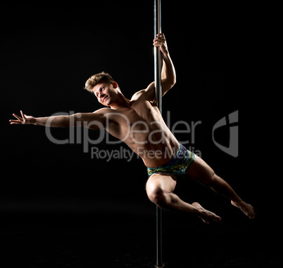 Smiling guy posing while performing trick on pole