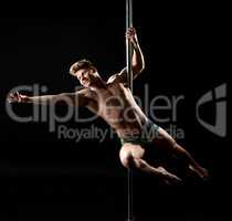 Smiling guy posing while performing trick on pole
