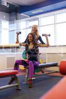 Girl helps her friend to workout with dumbbells