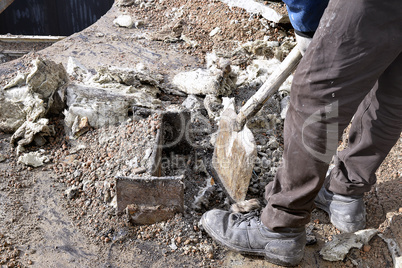 Unknown worker with a shovel clearing construction debris