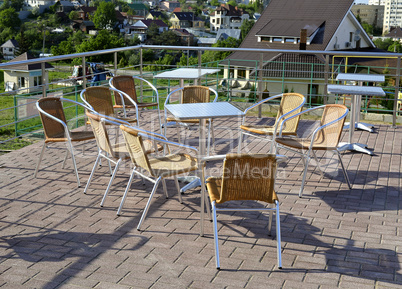 Wicker chairs with metal legs and racks are in an open cafe area