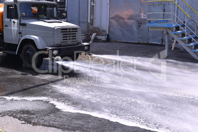 Water truck watering the asphalt at a manufacturing plant for du