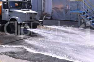 Water truck watering the asphalt at a manufacturing plant for du
