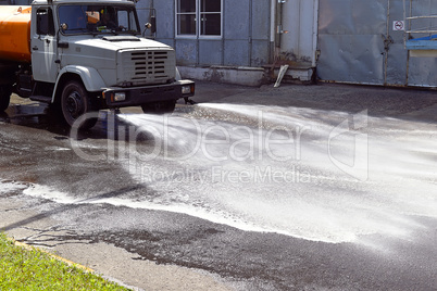 Water truck watering the asphalt at a manufacturing plant for du