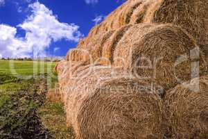 Rolls of hay stacked in a stack on the field against the blue sk