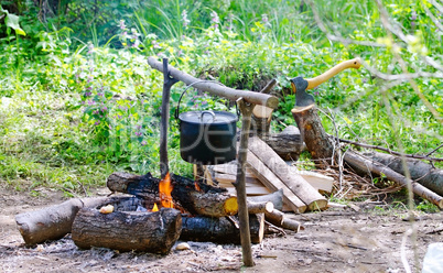 Tourist pot of water hanging over a fire of wood in the Camping