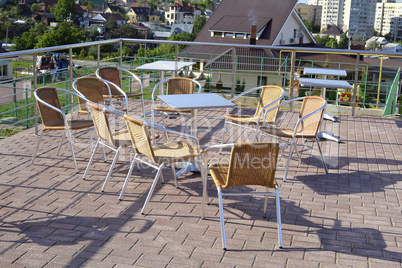 Wicker chairs with metal legs and racks are in an open cafe area