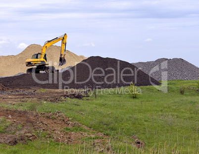 Yellow excavator working digging in sand quarry