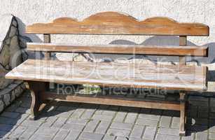 Old wooden vintage empty bench standing on an open paved area