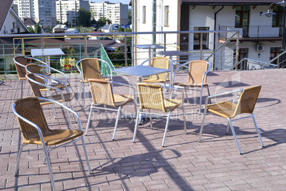 Wicker chairs with metal legs and racks are in an open cafe area