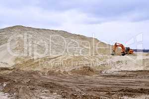 Working digger in a quarry produces sand