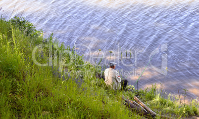 A fisherman with a fishing rod on the river bank