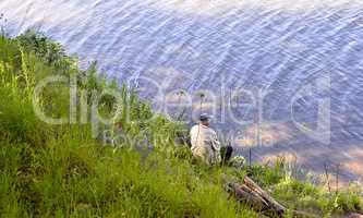 A fisherman with a fishing rod on the river bank