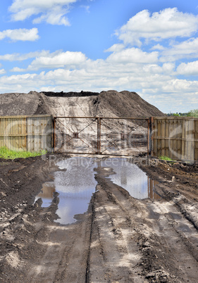 Dirt road, a pool and a lot of stored in the open air ground for a closed fence
