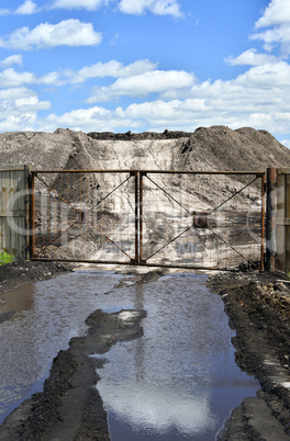 Dirt road, a pool and a lot of stored in the open air ground for a closed fence