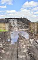 Dirt road, a pool and a lot of stored in the open air ground for a closed fence