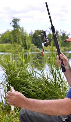 Close up of guy sitting on bridge and fishing