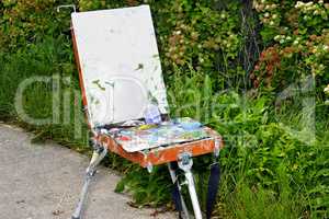 Hands of the artist with a brush, paint a picture on an easel in the open air