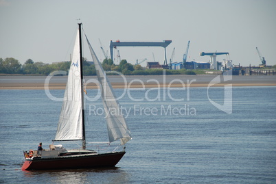 Segelschiff in der Elbe vor einer Werft