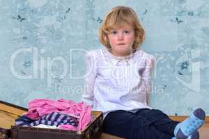 Little girl with clothes suitcase