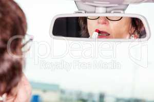 Woman looks in the rearview mirror of her car