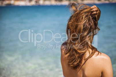 long blonde red hair girl wathckng at the sea with a hand over h