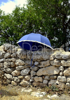 Blue umbrella on ancient wall of ruins of Acinipo in Ronda