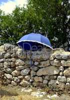 Blue umbrella on ancient wall of ruins of Acinipo in Ronda