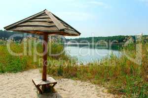 wooden umbrella on the sand near lake in the forest
