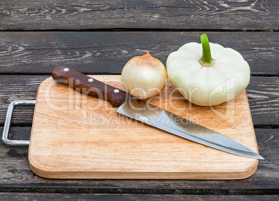 Onions, squash and knife on board
