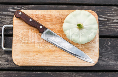 Squash on a cutting board  wooden background with  steel knif