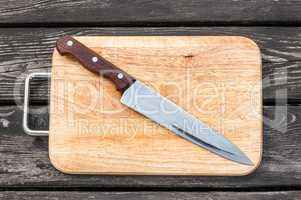 Steel knife on a cutting board  wooden background with