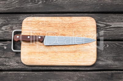 Steel knife on a cutting board  wooden background with
