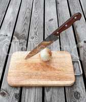 Knife,onion and a cutting board  on  wooden table