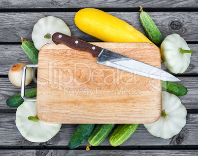 Cutting board, knife, fresh vegetables on wooden table.  Top vie