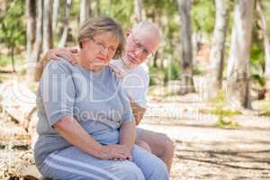 Depressed Senior Woman Sits With Concerned Husband Outdoors